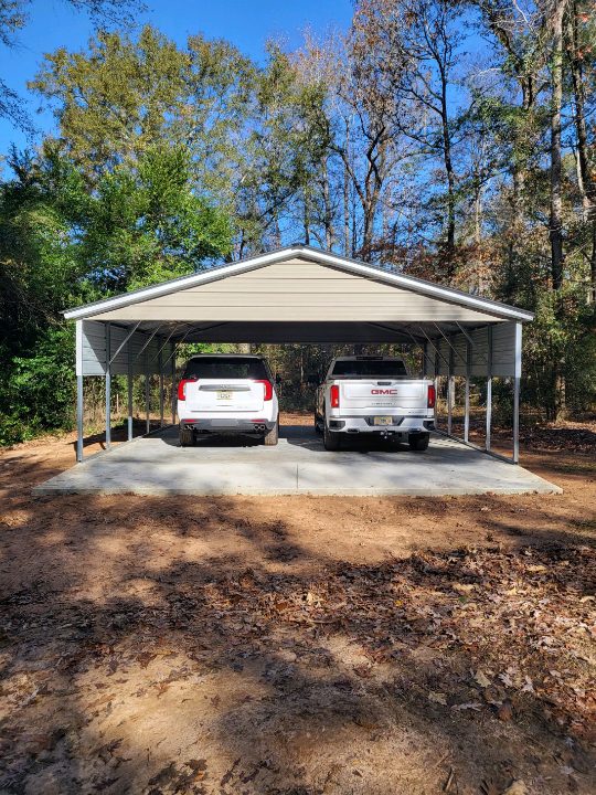 Two cars parked in a carport on the side of a road.