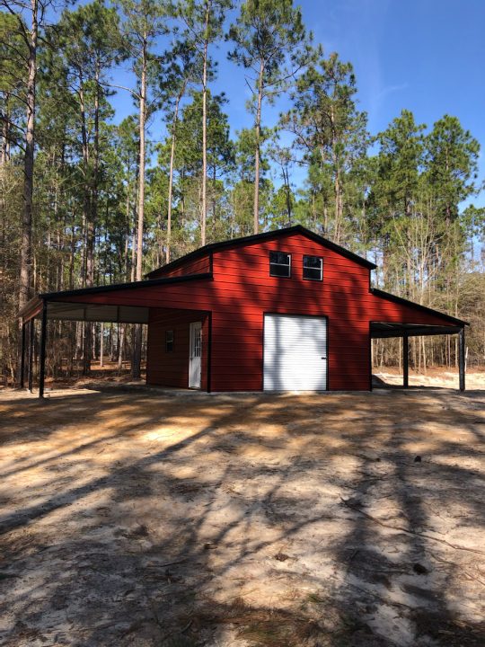 A red barn with a white door and black roof.