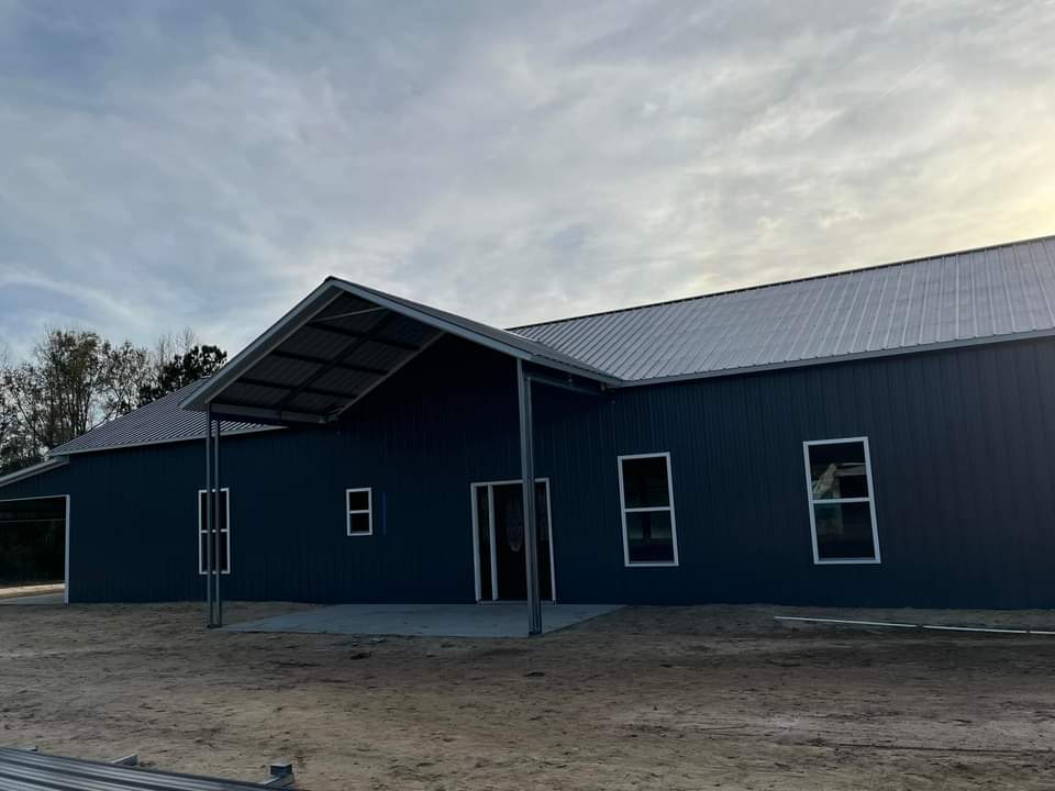 A dark blue metal building with a porch.