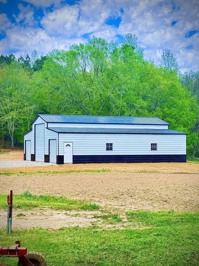 A white barn with black trim sits in a grassy field.