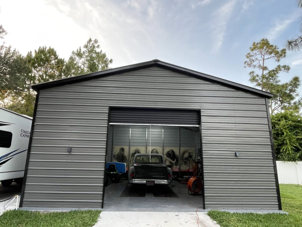 A gray metal garage with a black garage door.