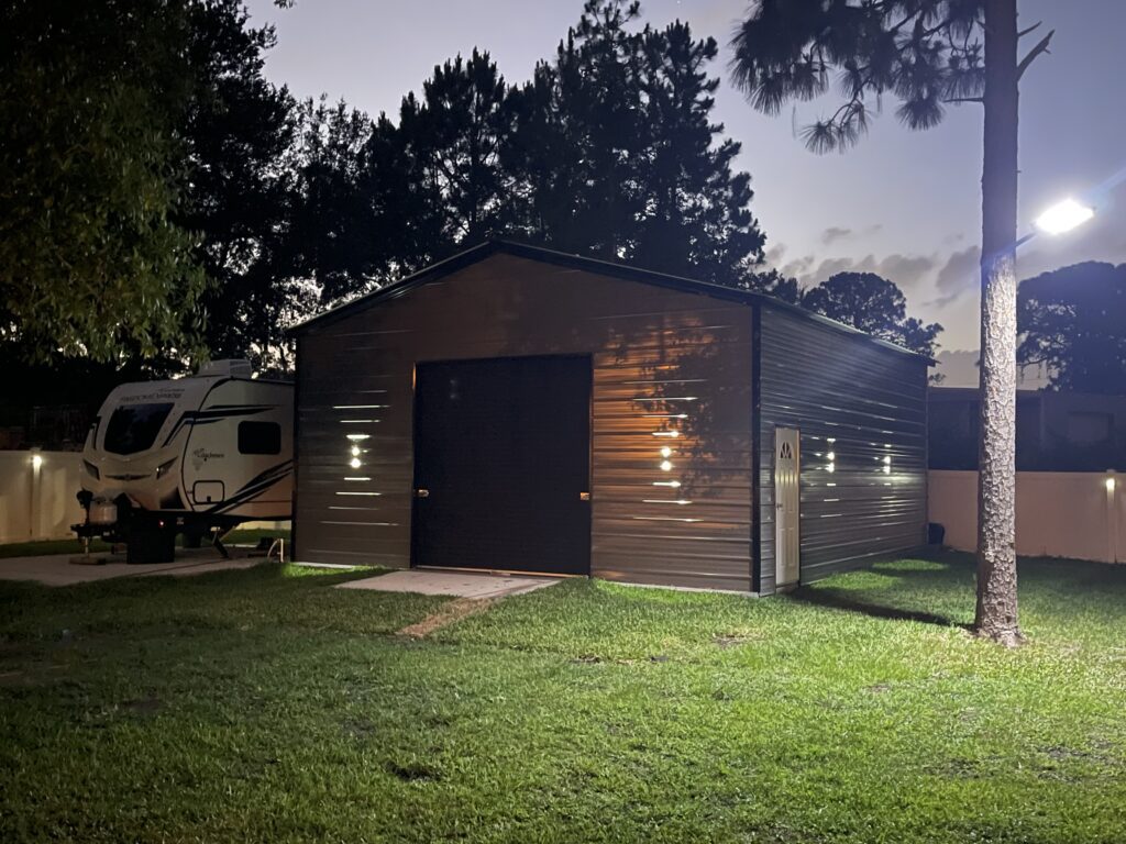 A metal building with a camper parked next to it.